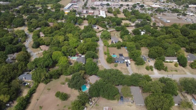 Dense forest canopy envelops private estate properties near Ten Mile Creek greenbelt. Narrow country lanes guide travel past shaded ranch dwellings, blue swimming pools, DeSoto, Texas