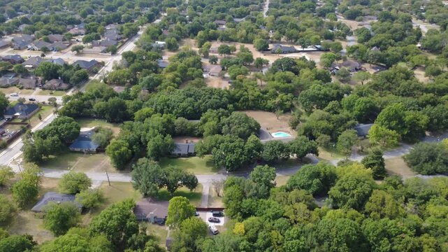 Interconnected suburban avenues link quiet residential courts near Polk Street. Brick residences, dark shingle roofs integrate into mature deciduous hardwood canopies, DeSoto, Texas