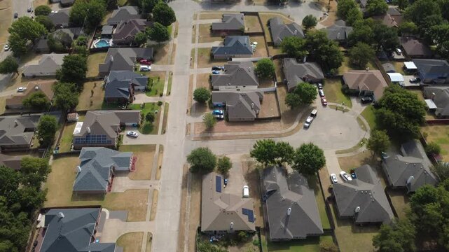Symmetric suburban cul de sacs align along paved neighborhood streets near Hampton Road. Solar rooftop panels, parked vehicles border well maintained brick family homes, DeSoto, Texas