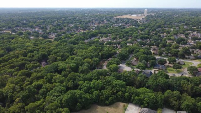 Curving neighborhood lanes weave across Meadowbrook residential subdivision. Clustered single family brick homes sit nestled under shady oak trees near civic water towers, DeSoto, TX
