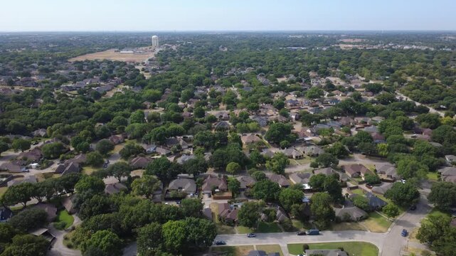 Expansive hardwood canopy envelopes quiet suburban neighborhoods along Pleasant Run Road. Continuous green treetops shade single family residential roofline structures, DeSoto, Texas