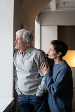 Concerned elderly man with distant gaze avoiding conversation with wife trying to connect. Senior trouble, marital tension, emotional distance, health struggle, silent conflict, old couple late life