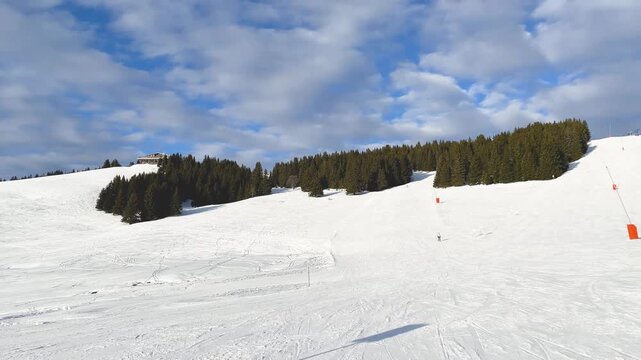 Wide view of a snowy ski slope in Megeve, located in the French Alps, Haute-Savoie, France. The landscape captures the essence of a popular European winter sports destination.