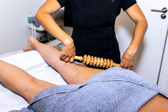 Therapist providing wood therapy massage on woman's leg for wellness and skin care