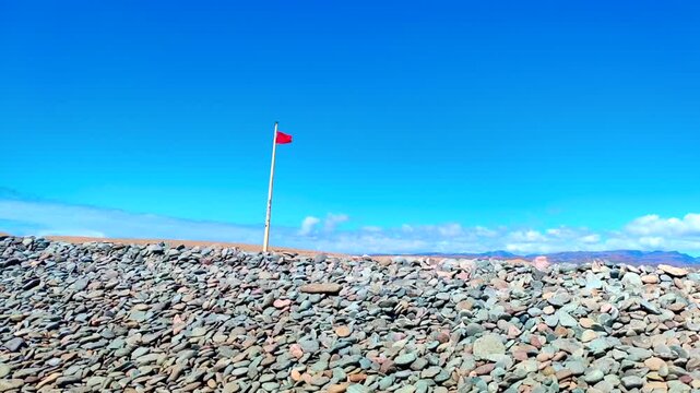 Spanish national flag waving in slow motion on flagpole against clear blue sky in Spain