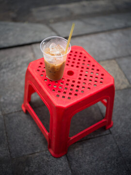 Vietnamese Iced Coffee C&agrave; Ph&ecirc; Sữa Đ&aacute; on Red Plastic Stool on Pavement, Vietnam