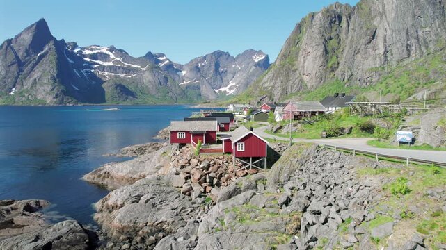Iconic red wooden cabins, known as rorbuer, standing on stilts along the rocky coast of a fjord in the Lofoten Islands, Norway