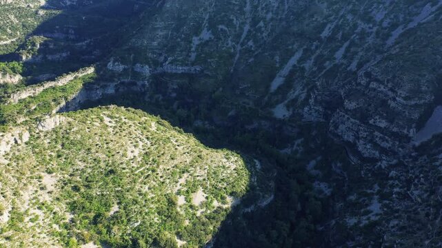 A high-angle aerial shot showcasing the dramatic limestone canyon landscape of Cirque de Navacelles in Occitanie, southern France.
