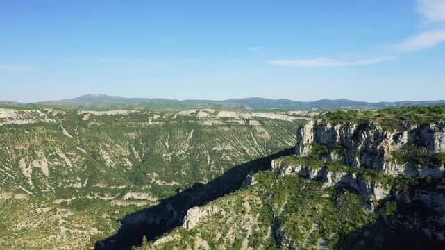 Wide aerial footage showcasing the dramatic limestone cliffs and deep canyon of the Cirque de Navacelles, located in the Occitanie region of southern France.