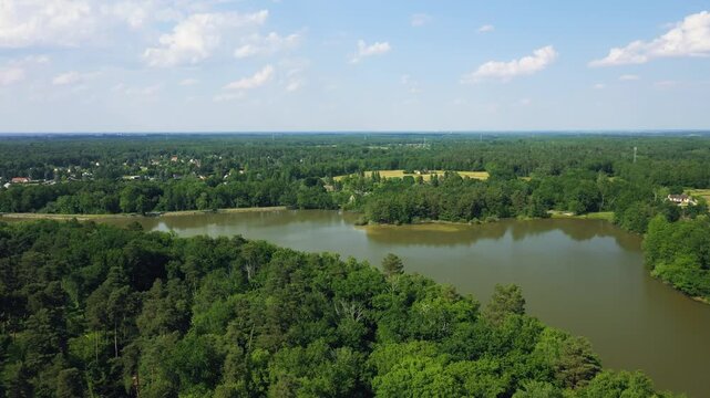 Aerial footage of Etang du Gue l'Eveque, a tranquil lake surrounded by dense green forest near Dampierre-en-Burly in the Centre-Val de Loire region, France.