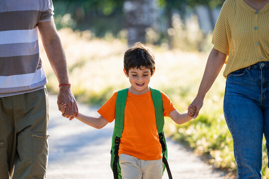 Little boy holding hands with family going to school