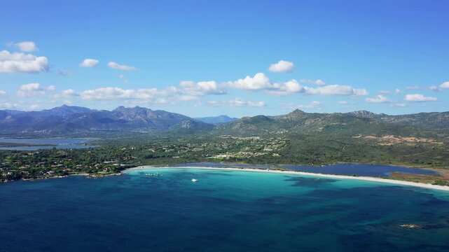 Aerial footage showcasing the stunning Spiaggia Lu Impostu beach near San Teodoro, Sardinia, Italy. The video captures turquoise waters, white sandy shoreline, lush green vegetation.