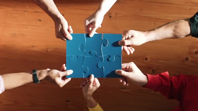 Top down view of skilled business people assemble blue jigsaw puzzle on meeting table. Group of diverse team working together to solve the puzzle. Represented togetherness, cooperative. Convocation.