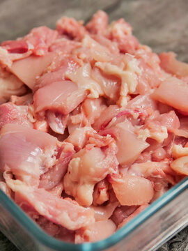 Fresh, diced raw chicken fillets pieces in clear glass bowl. Meat looks juicy, well-cut, ready for cooking. Ideal for recipe websites, food blogs, or culinary content