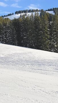 Vertical 9:16 video showing a sunlit ski slope with fresh snow and ski tracks in Megeve, Haute-Savoie, France. No people are visible. Captured in vertical format.