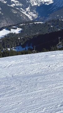 Vertical 9:16 video showing a snowy ski slope with chairlift infrastructure in the foreground, set against a dramatic backdrop of the Mont Blanc Massif in the French Alps.