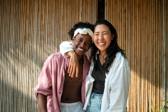 Diverse pair of friends, couple laughing together in a scenic coastal environment