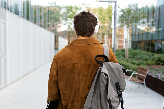 Student walking away listening to music with headphones and backpack