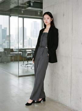 Professional Asian Businesswoman Leaning Against Concrete Wall in Modern Office Setting