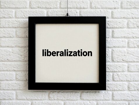 Black frame hangs on white brick wall. Minimalist poster shows word liberalization in bold black text. Simple decor for office modern gallery space. Concept of political freedom, economic change in
