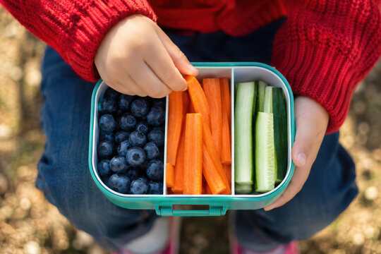 Close up of child hand taking carrot stick from healthy lunch box