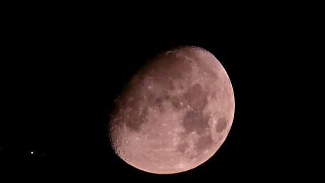 Slow motion silhouette of a commercial airplane flying across the glowing red moon at night.