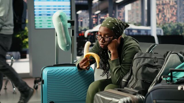 Tired woman eats banana in bus terminal during long distance journey