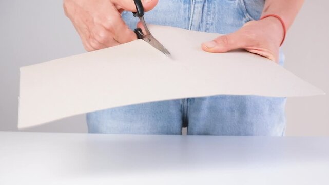 Close-up of a teacher cutting cardboard with scissors for DIY craft project. Creative hands-on learning activity promoting education, imagination, handmade skills and creativity