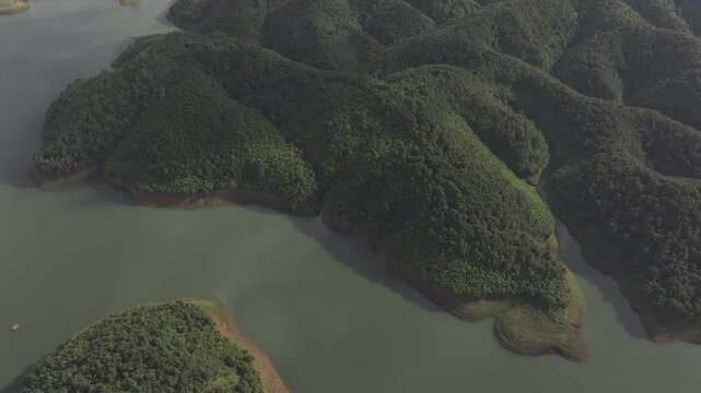 Aerial drone view of Ta Dung Lake surrounded by hundreds of green island hills and mountains in Ta Dung Commune, Lam Dong Province, Vietnam. View from QL 28. D Log mode