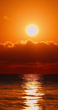 Golden Sunset Over Calm Ocean Horizon With Dramatic Clouds And Sunlight Reflection over water