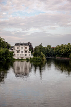 White lakeside villa reflected in the calm waters of the Feenteich in Hamburg, Germany.