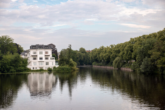 White lakeside villa reflected in the calm waters of the Feenteich in Hamburg, Germany.