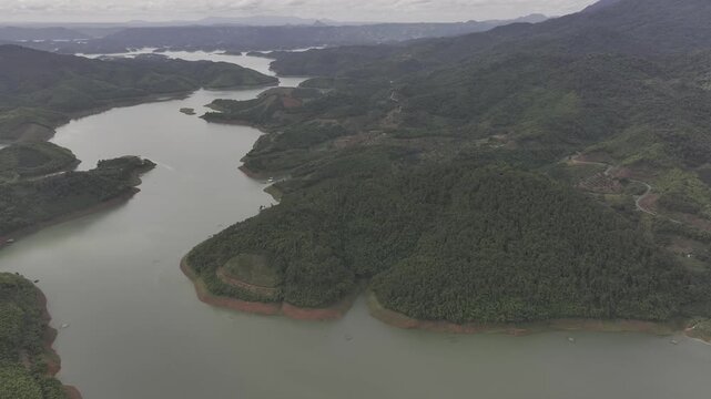 Aerial drone view of Ta Dung Lake surrounded by hundreds of green island hills and mountains in Ta Dung Commune, Lam Dong Province, Vietnam. View from QL 28. D Log mode