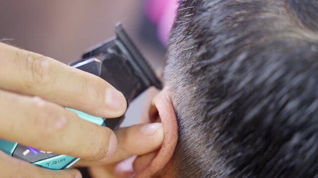 Barber giving a haircut with a clipper in a barbershop