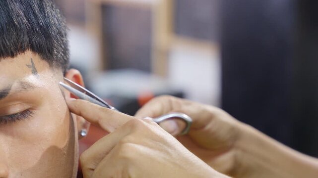 Professional barber cutting hair with scissors in barbershop