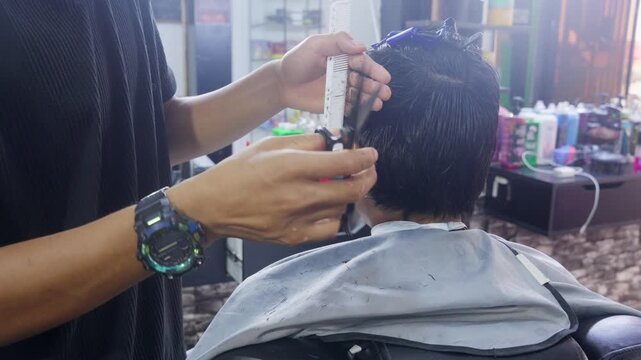 Professional barber cutting man's hair with scissors