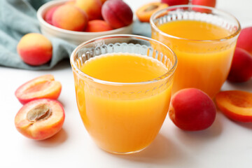 Apricot juice in glasses and fresh fruits on white table, closeup © New Africa