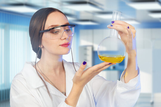 Chemical laboratory. Female scientist examines a liquid sample in a flask while conducting chemical research, testing and quality control.