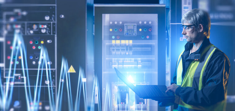 Electrical engineering. Technician uses a laptop to monitor switchgear, power distribution equipment and electrical system performance in a control room.