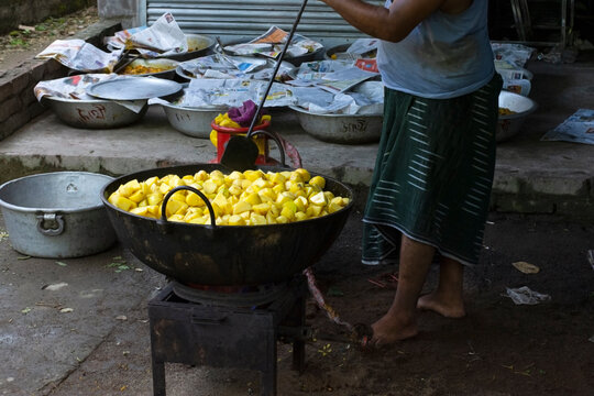 Indian Man Cooking Chopped Potatoes in a Large Wok