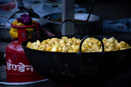 Indian Man Cooking Chopped Potatoes in a Large Wok