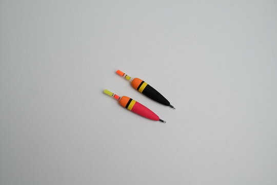 Two fishing floats one pink and one black, both with bright orange accents set against a white background, ready for fishing.