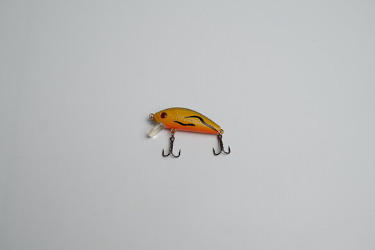 Bright orange yellow artificial fishing lure with sharp double hooks, isolated against a clean white background.