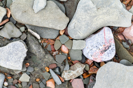 Quebec, Canada, 31 July 2026 : Smooth, wet, colorful pebbles and rocks of various sizes and shapes lie scattered on a natural surface.