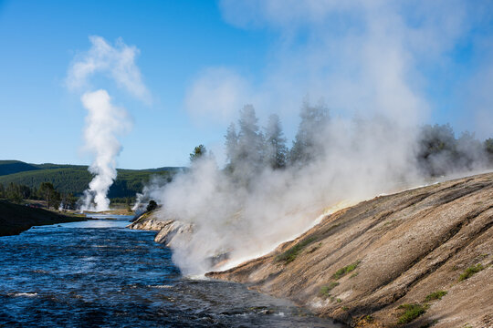 Morning in the midway gyser basin, fumaroles on Firehole river with hot steam rising, summer tourism at Yellowstone National Park viewing natural geothermal features
