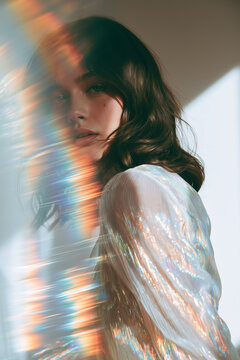 ethereal female brunette model with refracting rainbow light in iridescent silver fashion 