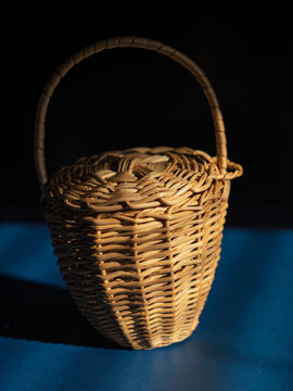Woven Rattan Basket with Handle on Blue Surface