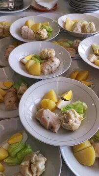 Vertical pan of mass catering preparation of Indonesian traditional siomay steamed dumplings and vegetables in bowls