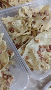 Vertical pan of traditional Indonesian crispy peanut crackers peyek kacang in plastic containers