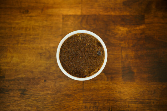 Ground coffee in white cupping bowl on dark wooden table